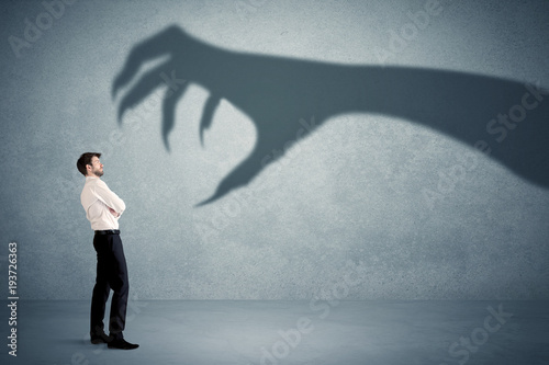 Fotografie Business person afraid of a big monster claw shadow concept