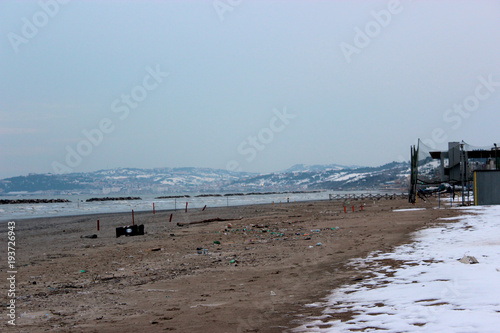 spiaggia con la neve e paesaggio collinare 