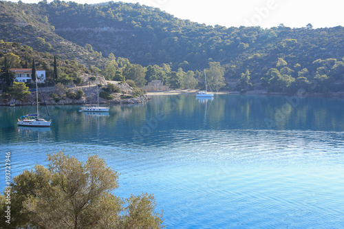 Fototapeta Naklejka Na Ścianę i Meble -  Summer morning time sailboats anchoring in Russian bay Poros island Greece.