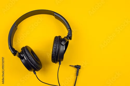Obraz czarne słuchawki na żółtym tle