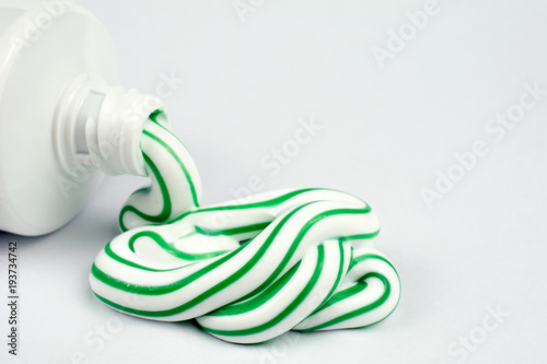 Green and white toothpaste squeezed out of a tube dental hygiene concept  close up  selective focus  white background