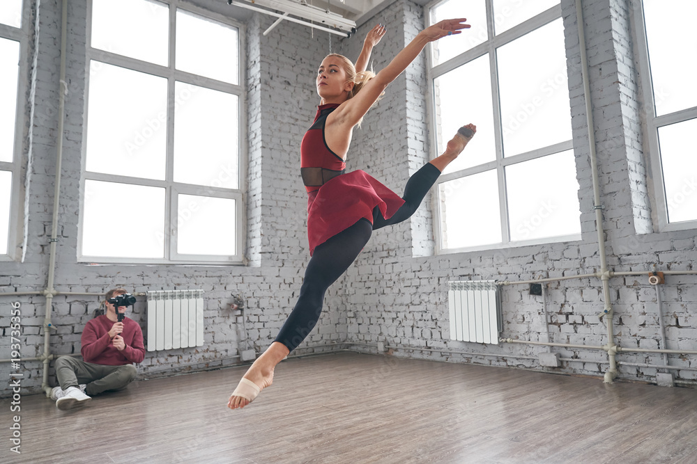 Fototapeta premium Young female dancer jumping and dancing in the gym. fashion ballet dancer. studio shot