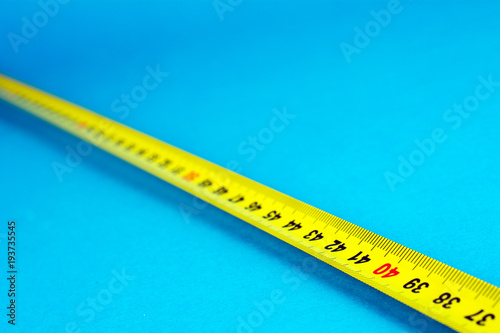 yellow Measuring tape on a blue background selective focus close-up copy space