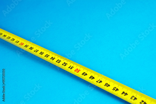 yellow Measuring tape on a blue background selective focus close-up copy space