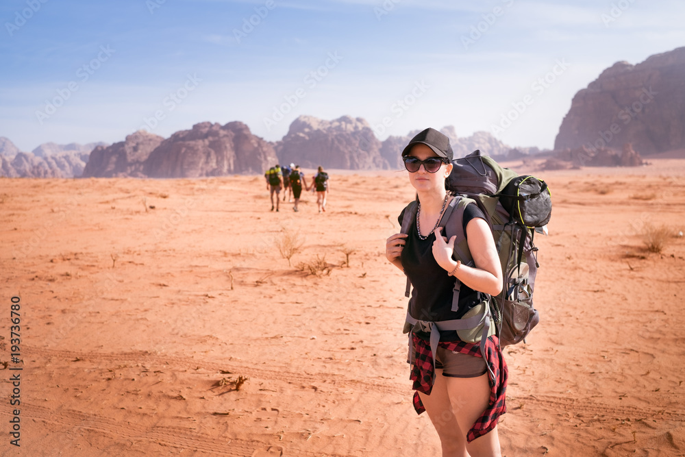 Tourist woman with friends in a desert. Jordan natural park Wadi Rum. Backpacker on the road. Woman hiker with backpack 