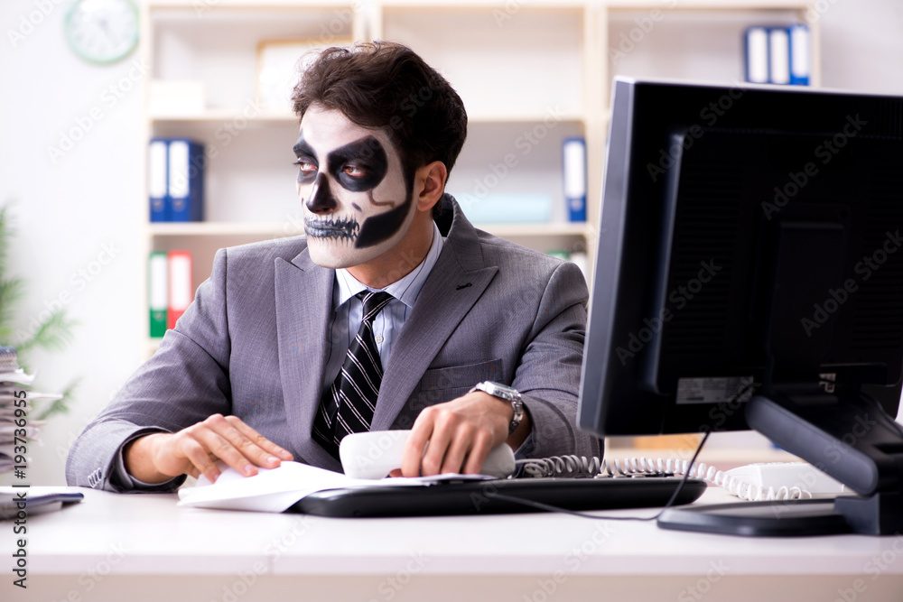 Businessmsn with scary face mask working in office Businessmsn with scary face mask working in office