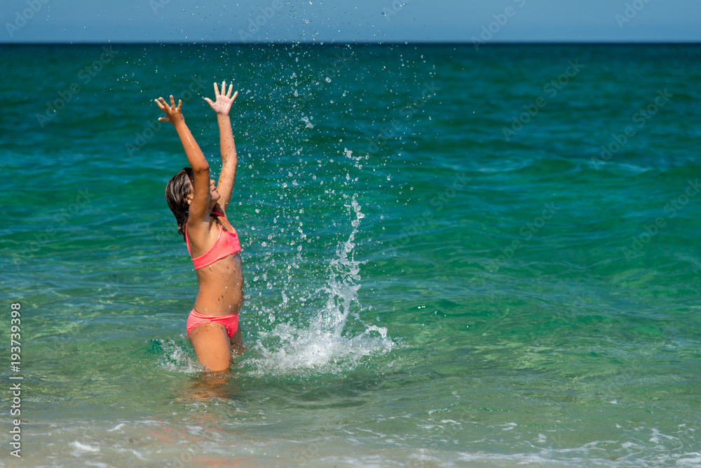 Girl having fun bathing in to the sea and splashing water