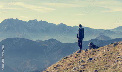 Lonely hiker standing and looking into distant mountains.