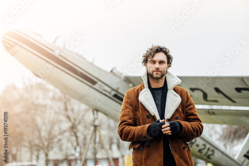 handsome man with old airplane behind outside