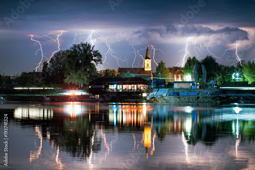 Lightning behind small town in Serbia reflected in river Tisza.