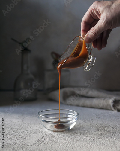 Pouring caramel sauce. Vertical. Selective focus.