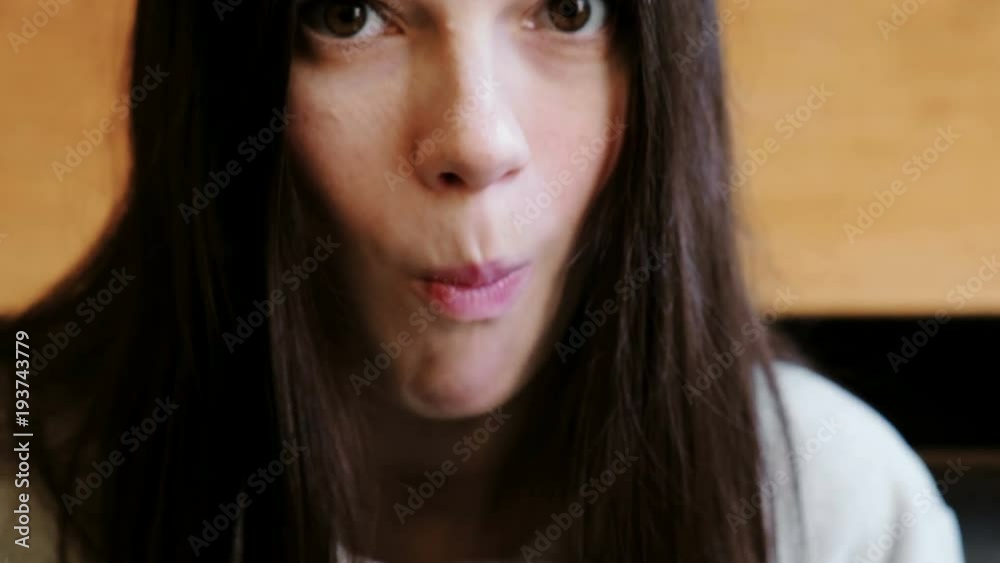 Close-up brunette woman's face eating tomato looking at camera and smiling.