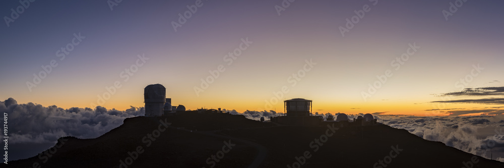 view from the summit of haleakala on the island of maui in hawaii in the pacific ocean showing the haleakala observatory against a stunning sunset and beautiful blue sky