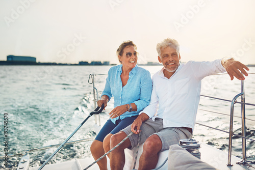 Smiling mature couple sailing their boat on a sunny afternoon © Flamingo Images
