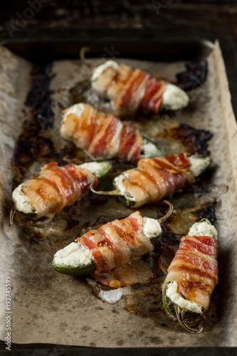 Vegetables stuffed with cheese and bacon and baked on tray in oven. Rustic recipe food on wooden background. Top view