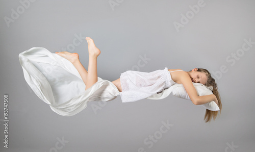 Sleeping girl. Flying in a dream. White linen flying through the air. photo