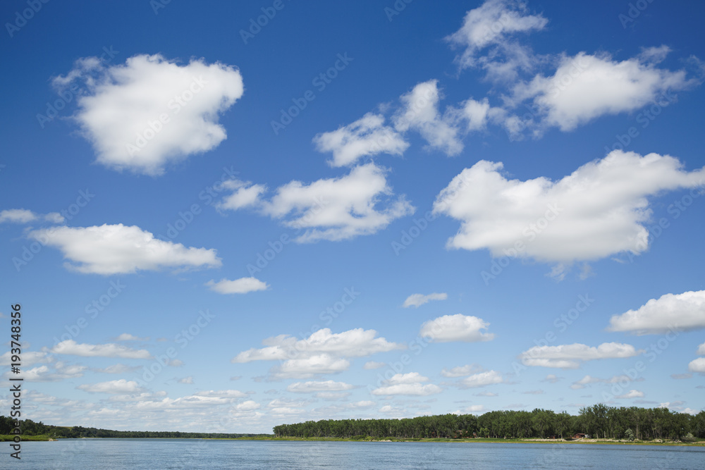 Puffy white clouds over the river in the summer