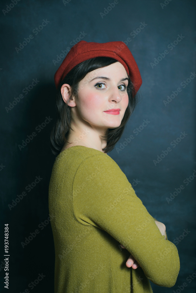 woman in red beret and green dress on the black wall background woman in red beret and green dress on the black wall background