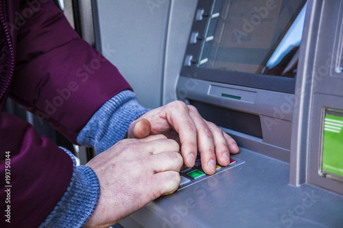 Hands typing PIN at ATM machine for cash money withdrawal
