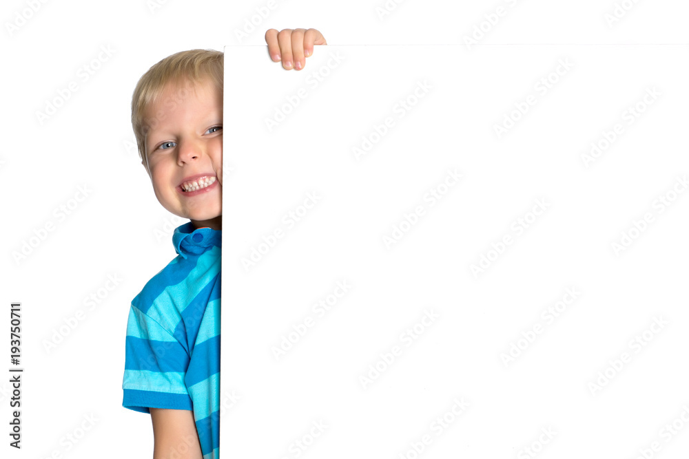 A little boy is looking from behind an empty banner. A little boy is looking from behind an empty banner.