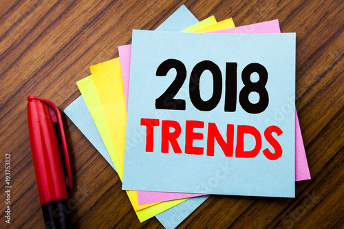 Handwriting Announcement text 2018 Trends.  Concept for Trending Data Prediction Written on sticky stick note paper with wooden background with space office view with pencil marker