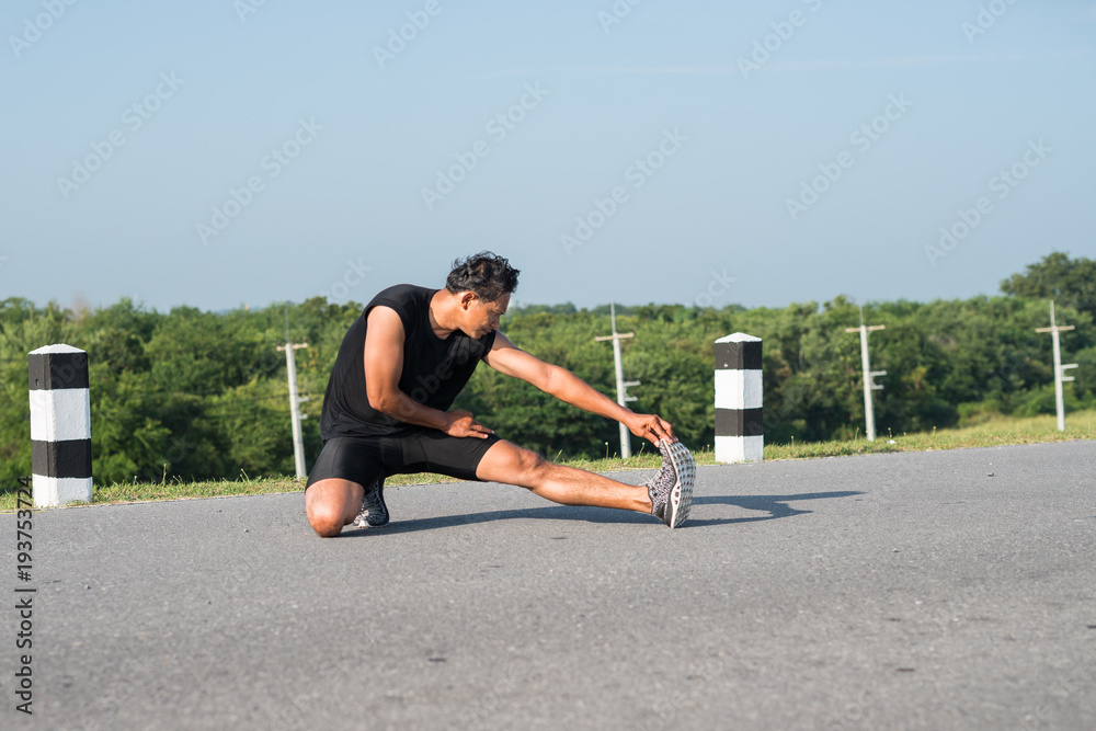 Naklejka premium Male runners are stretching the leg muscles to prepare for a run in the morning. The concept of health and fitness