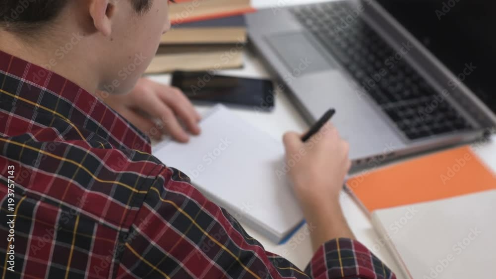 Schoolboy drawing letters in his notebook in neat handwriting, doing homework Schoolboy drawing letters in his notebook in neat handwriting, doing homework