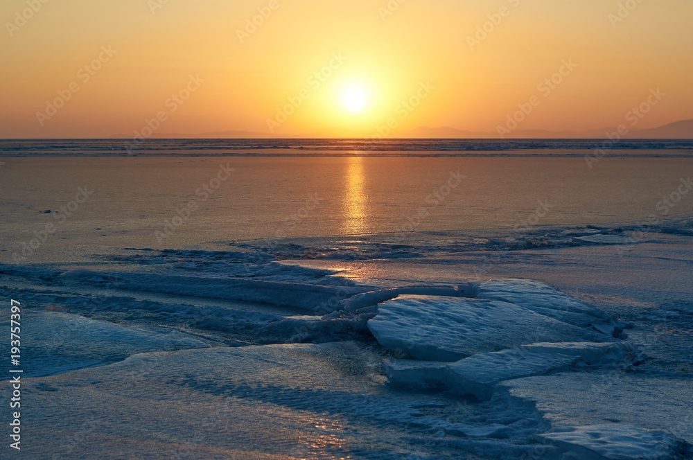Winter sunset over frozen bay.