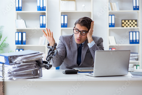 Fotografie Busy employee chained to his office desk