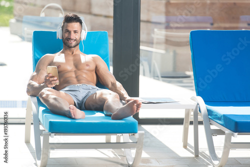 Athlete Resting On Sun Lounger and Listening Music