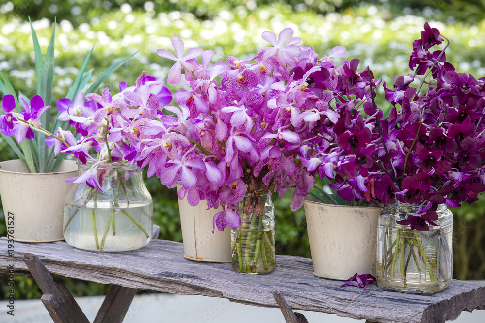 Bouquets orchid flowers in the tropical yard on a wooden table