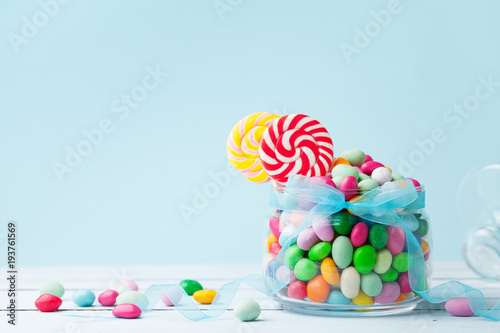 Jar staffed sweet colorful candy against turquoise background. Gifts for Birthday party.