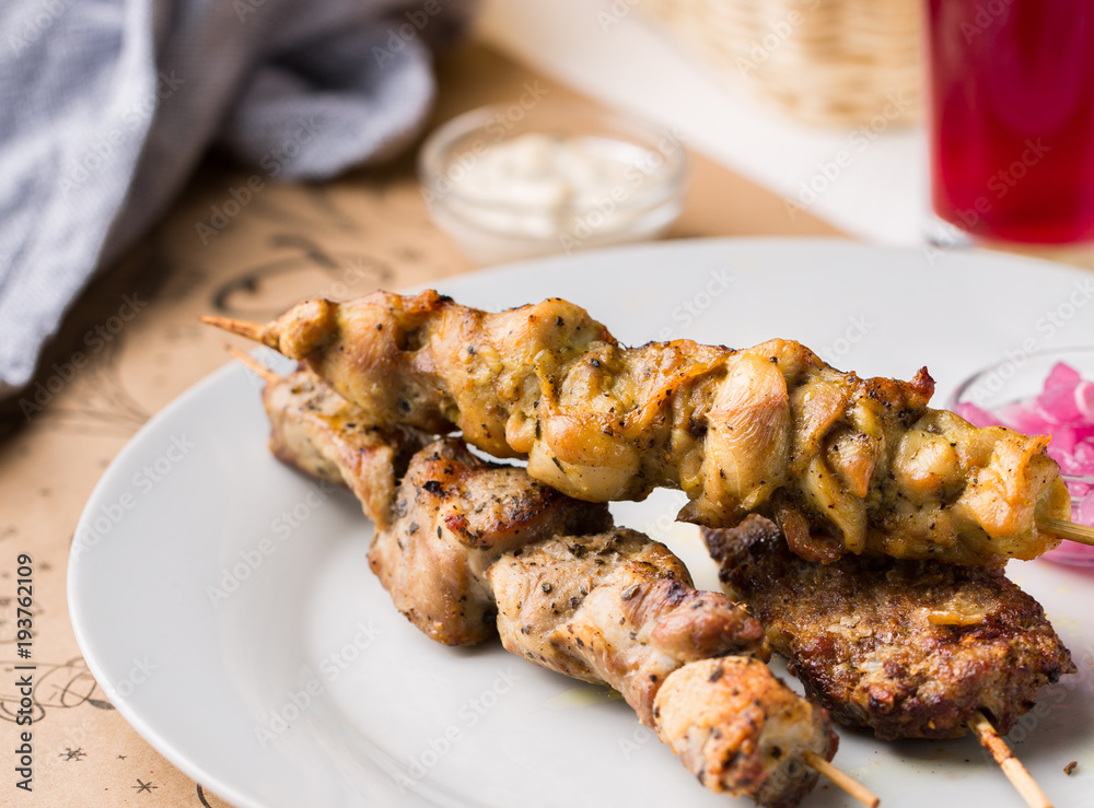 Assorted delicious grilled meat with sauces on white plate. BBQ plate with different kinds of meat. Street fast food. Assorted delicious grilled meat with sauces on white plate. BBQ plate with different kinds of meat. Street fast food.