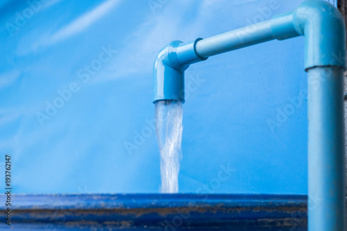 Foto Blue pvc pipe with flowing water in bucket