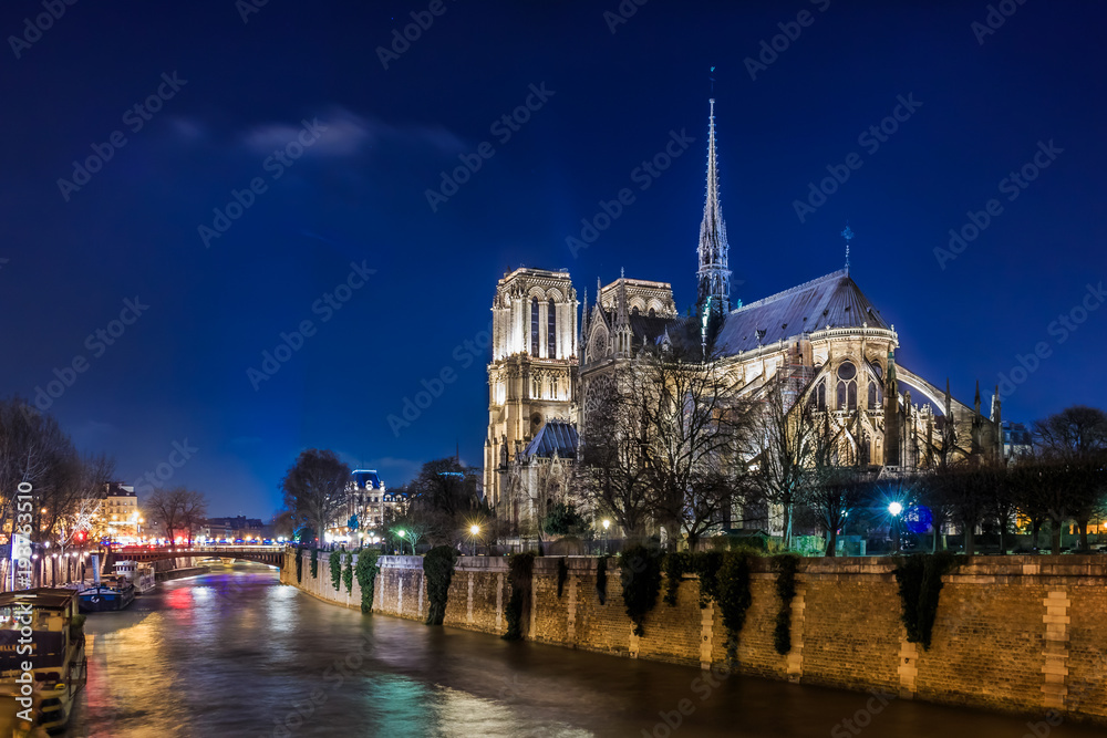 View over Seine onto illuminatred back side of Notre Dame de Paris at night in Paris France