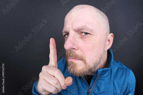 Schilderij op canvas strict bearded man with a pointing finger on gray background.