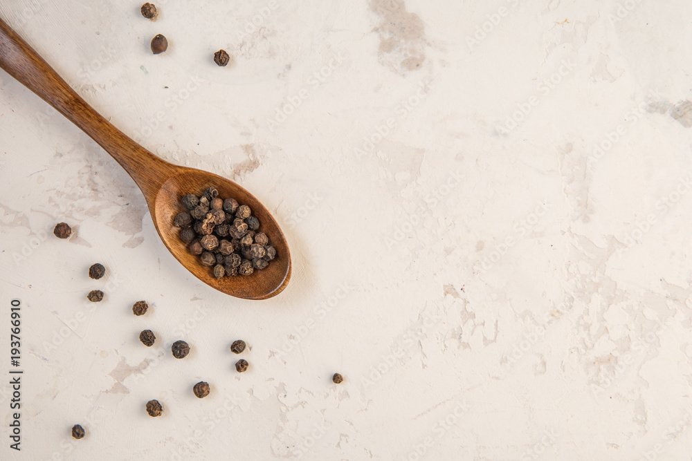 Black pepper peas on a wooden spoon, light background Black pepper peas on a wooden spoon, light background