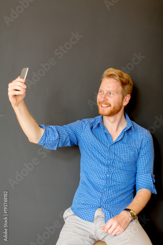 Ginger man taking selfie is...