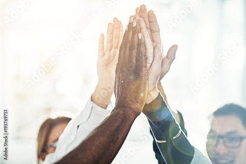 Diverse businesspeople high fiving together in an office