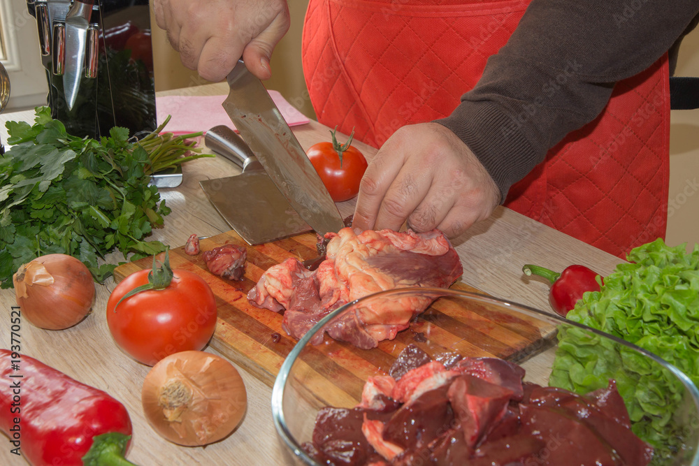 he is cutting meat or steak for a dish on wooden board