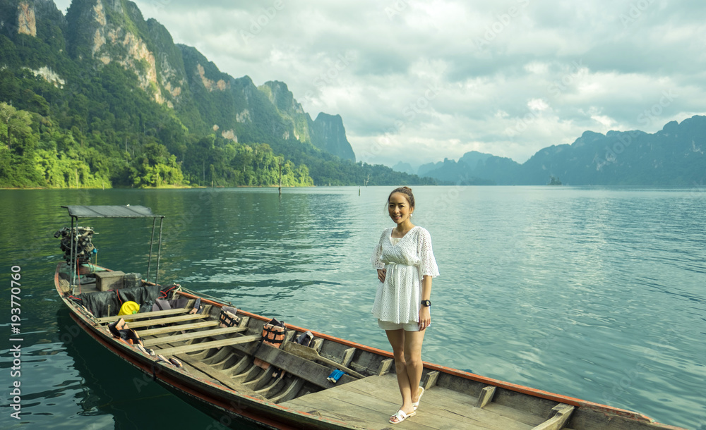 girl posing smile and relaxing by stand on the boat tail in the beautiful lake with background