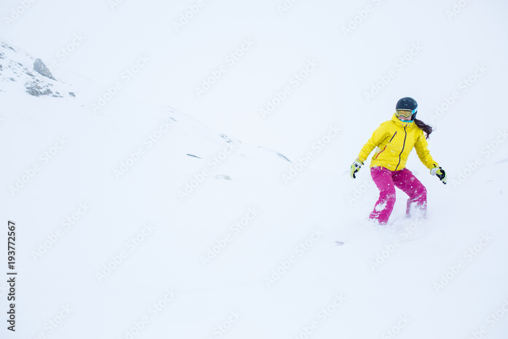 Image of female athlete wearing helmet with developing hair snowboarding from mountain slope