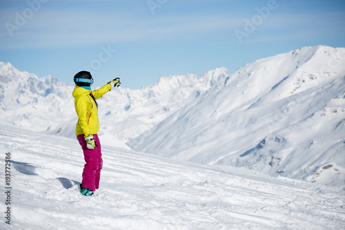 Photo of woman in helmet showing her hand in distance on mountains
