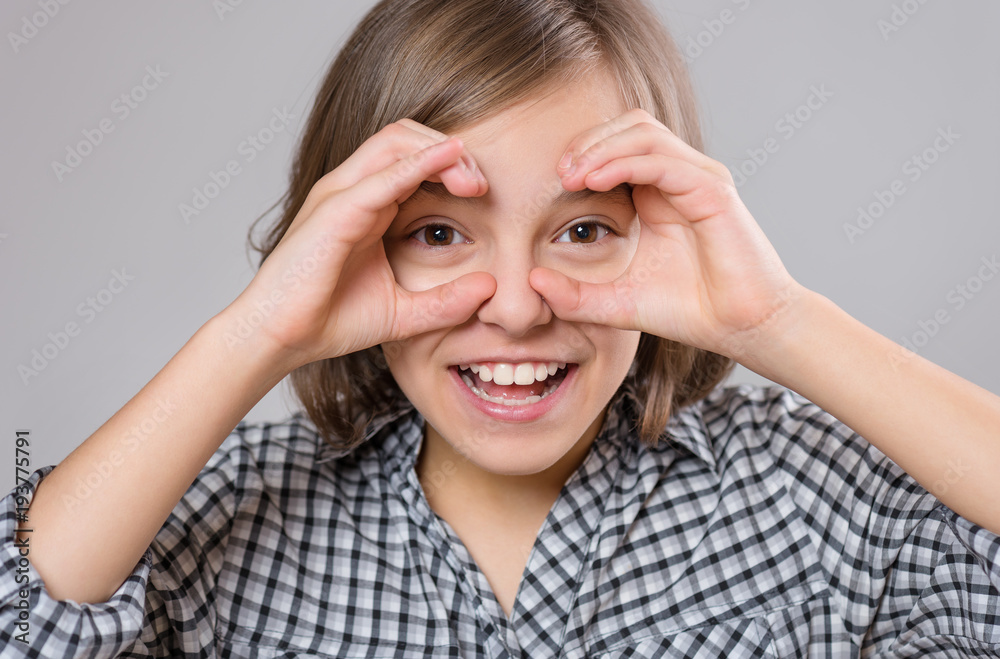 Close-up emotional portrait of caucasian little girl. Funny kid making binoculars using her hands, on gray background. Beautiful child laughing looking very happy. Close-up emotional portrait of caucasian little girl. Funny kid making binoculars using her hands, on gray background. Beautiful child laughing looking very happy.