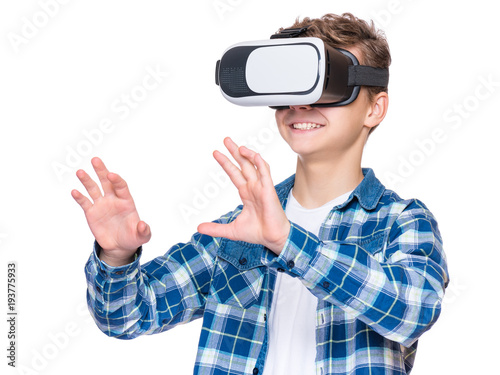 Happy teen boy wearing virtual reality goggles watching movies or playing video games. Cheerful smiling teenager looking in VR glasses. Funny child experiencing 3D gadget technology - close up.