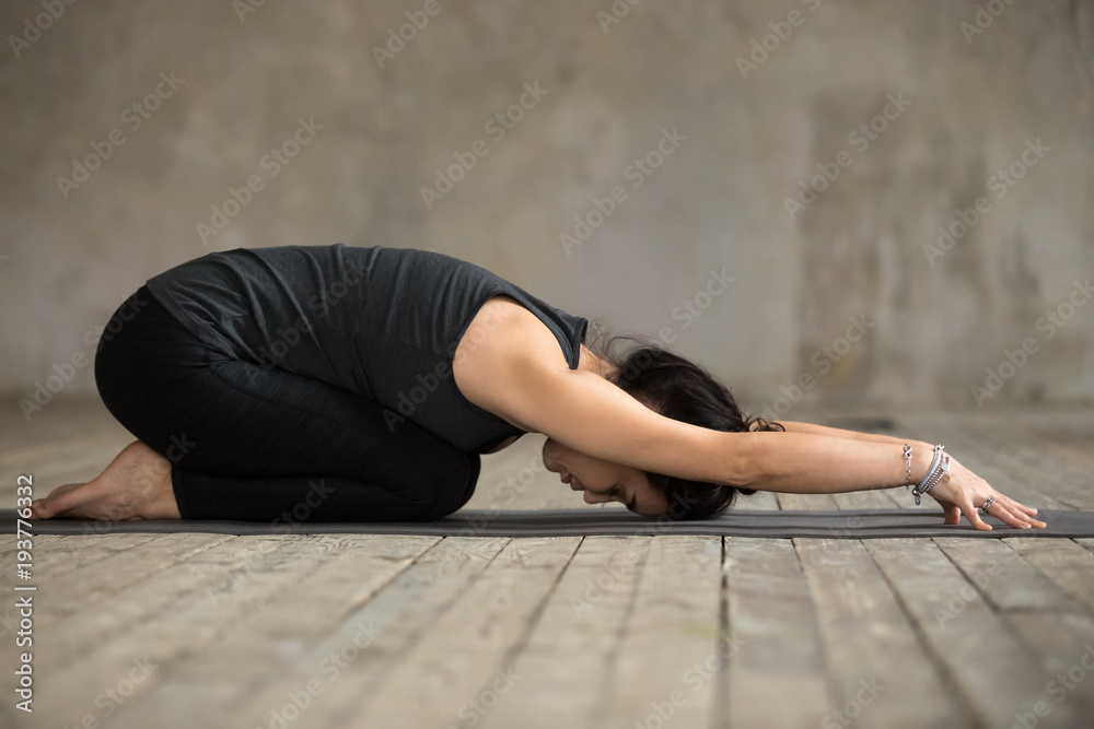 Young woman practicing yoga, doing Child exercise, Balasana pose, working  out, wearing sportswear, black pants and top, indoor full length, gray wall  in yoga studio Stock Photo | Adobe Stock