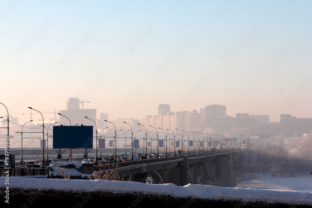 Winter day, the bridge and city in fog