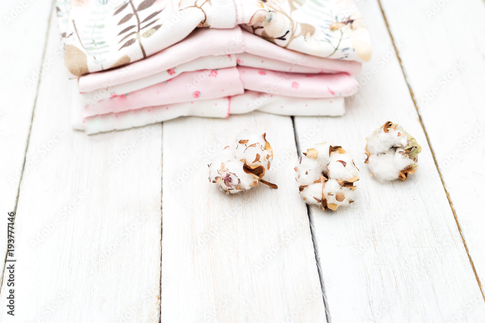 Fototapeta premium Baby clothes from organic cotton and cotton flower on wooden background. Flat lay