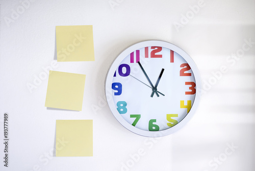 stick memo notes and a clock on white concrete wall photo