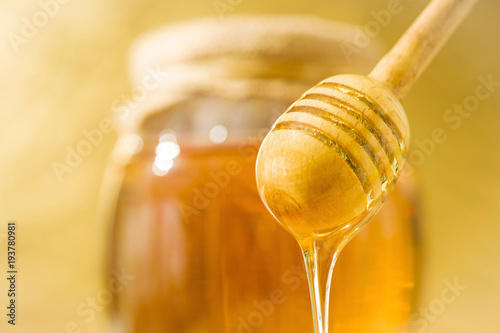 A honey spoon against the background of a jar filled with honey